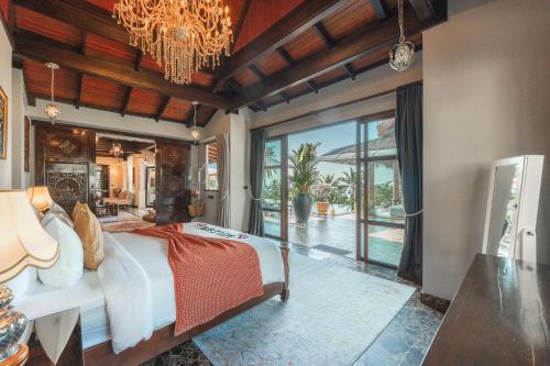 a bedroom with a large bed with a chandelier at Arun Rapee Villa Surin Beach in Surin Beach