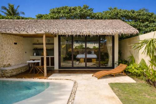 a house with a swimming pool and a straw roof at Nala Villas in General Luna
