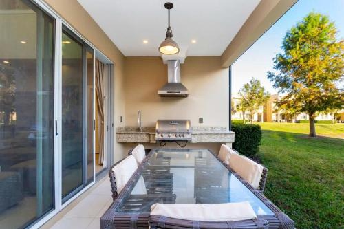 a patio with a glass table and a grill at Stunning 4Bd Close to Disney @ Magic Village 7614 in Orlando