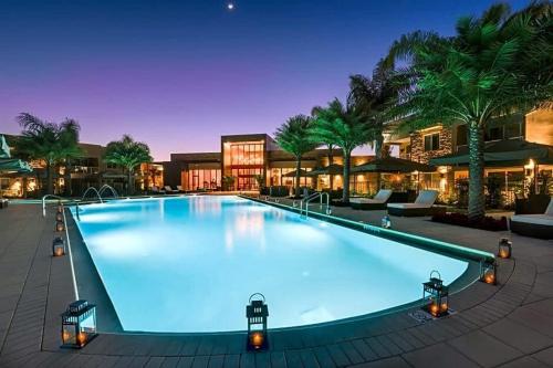 a large swimming pool with blue water at night at Stunning 4Bd Close to Disney @ Magic Village 7614 in Orlando
