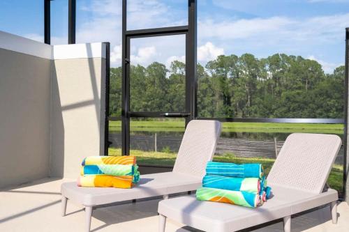 two white chairs with colorful pillows sitting in front of a window at Marvelous 4Bd w Pool Close to Disney at Storey Lake 2629 in Kissimmee