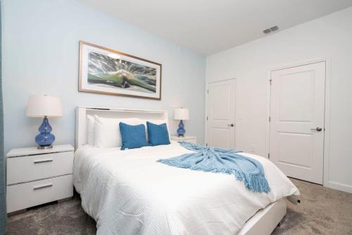 a bedroom with a large white bed with blue pillows at Marvelous 4Bd w Pool Close to Disney at Storey Lake 2629 in Kissimmee