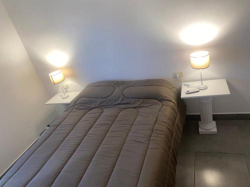 a bed in a room with two tables and two lamps at El Remanso de Paracao in Paraná