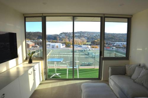 a living room with a couch and a large window at Prime Luxury Penthouse Living in Launceston