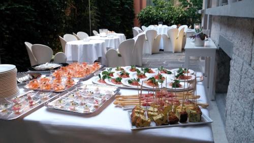 a buffet of food on a table with white chairs at Petronilla - Hotel In Bergamo in Bergamo
