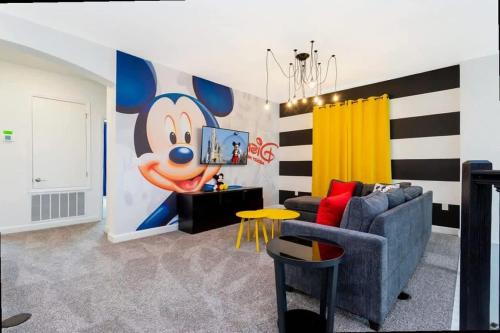a living room with a mickey mouse mural on the wall at Stunning Family Friendly 5 Bd w/ Pool Close to Disney @ Storey Lake 4242 in Kissimmee