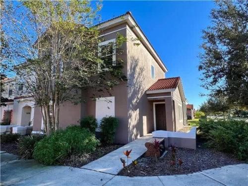 a white house with a tree and a driveway at Four Bedroom w/ Screened Pool Close to Disney 4572 in Kissimmee