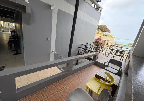 a balcony with a yellow table and chairs on a building at BW Guesthouse in Ko Tao