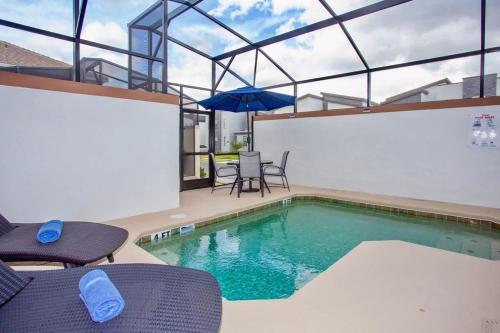 a swimming pool with two chairs and an umbrella at Wonderful 5 Bedroom w/ Pool Close to Disney 4801 in Kissimmee