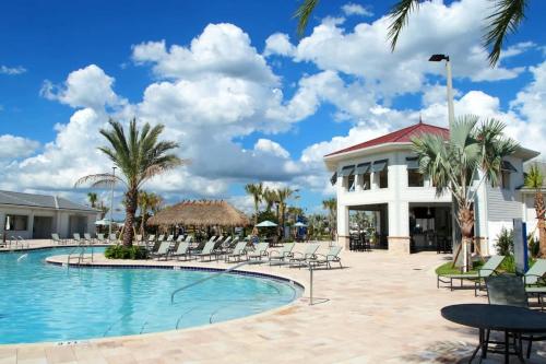 a pool at a resort with chairs and a building at Four Bedrooms close to Disney w Pool 4898 in Kissimmee