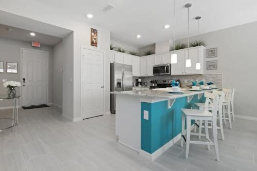 a kitchen with white cabinets and a blue island with stools at Four Bedroom with GameRoom 5150A in Kissimmee