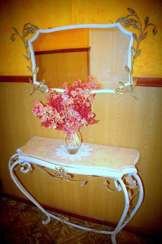 a vase of flowers on a table with a mirror at Hotel Mallorca in Mendoza