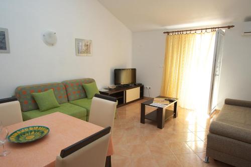 a living room with a green couch and a table at Apartments Novalja in Novalja