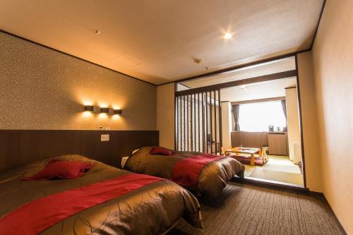 a hotel room with two beds and a window at Hotel Kanronomori in Niseko