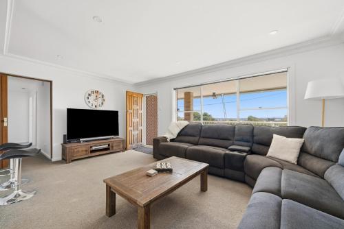 a living room with a couch and a tv at The Nelson Bay Getaway in Nelson Bay