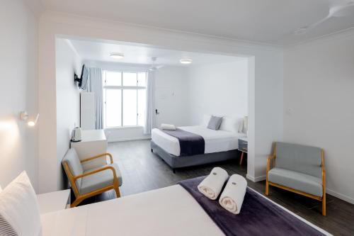 a hotel room with a bed and two chairs at Proserpine Motel in Proserpine