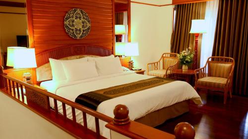 a bedroom with a large bed and two chairs at Felix River Kwai Resort - SHA Plus,Certified in Kanchanaburi