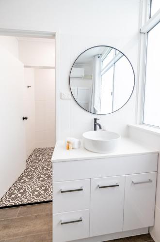 a white bathroom with a sink and a mirror at Proserpine Motel in Proserpine