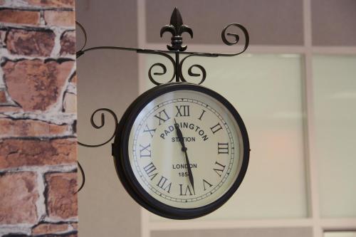 a clock is attached to a brick wall at London Mini-hotel in Yekaterinburg