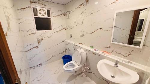 a white bathroom with a toilet and a sink at Sun Stayz Inn T - Nagar Chennai in Chennai