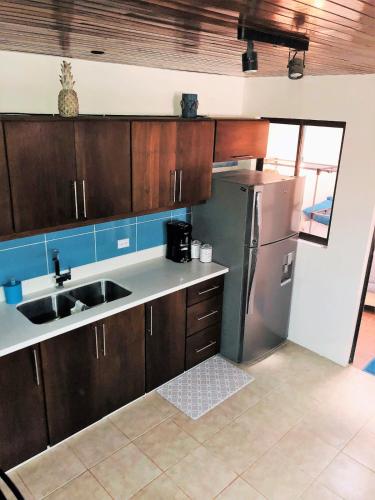 a kitchen with wooden cabinets and a stainless steel refrigerator at Tama Magico in Tamarindo
