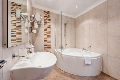 a white bathroom with a tub and a sink at Paradise Bay Resort in Mellieħa