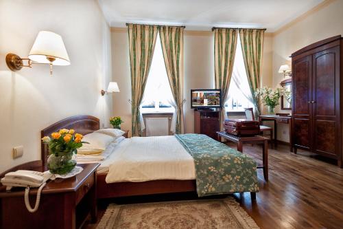 a bedroom with a bed and a table with flowers on it at Aparthotel Karmel in Kraków