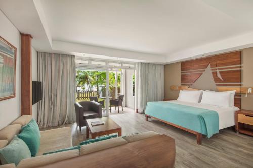 a hotel room with a bed and a couch at Shandrani Beachcomber Resort & Spa in Blue Bay