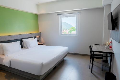 a bedroom with a bed and a desk and a window at Amaris Hotel Gorontalo in Gorontalo