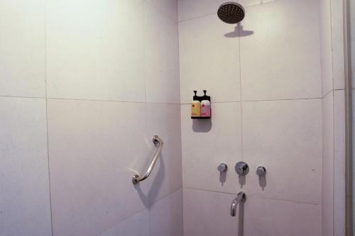 a white bathroom with a shower with a hand rail at Amaris Hotel Gorontalo in Gorontalo