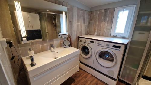 a bathroom with a sink and a washing machine at Nalle's in Stavtrup