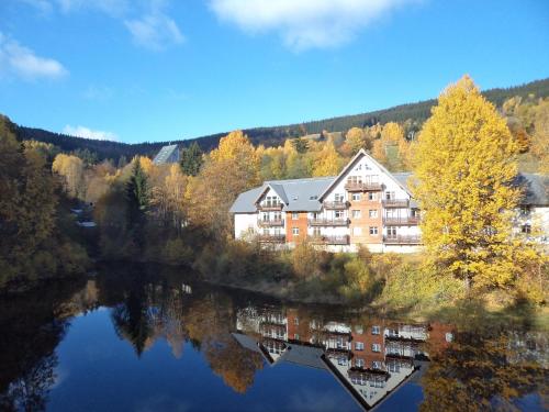 a reflection of a building in the water next to a lake at Apartmán Lucie Špindlerův Mlýn in Špindlerův Mlýn