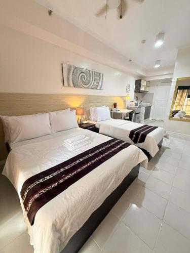 two beds in a large room with a kitchen at Cozy Studio Condo with Stunning Tagaytay Views in Tagaytay