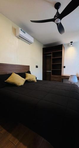 a bedroom with a black bed with a ceiling fan at Suites Oros in Oaxaca City