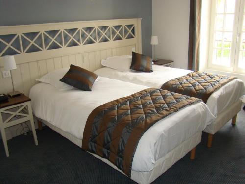 two beds in a hotel room with two at Logis Hotel, restaurant et spa Le Relais De Broceliande in Paimpont