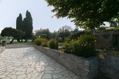 a stone walkway with flowers and a retaining wall at Villa Pioppi Hotel in Sirmione