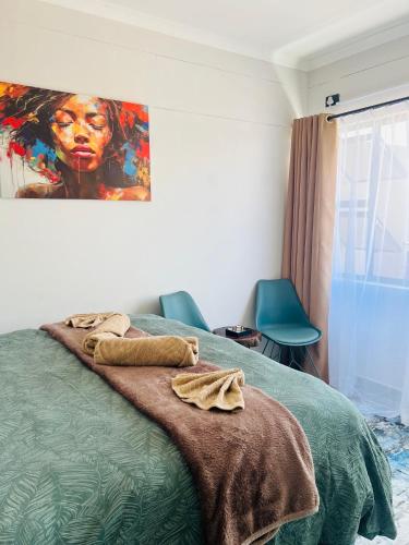 a bedroom with a bed with a painting on the wall at Ekuku retreat in Oshakati