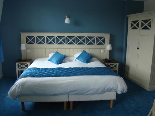 a bedroom with a large bed with blue walls at Logis Hotel, restaurant et spa Le Relais De Broceliande in Paimpont