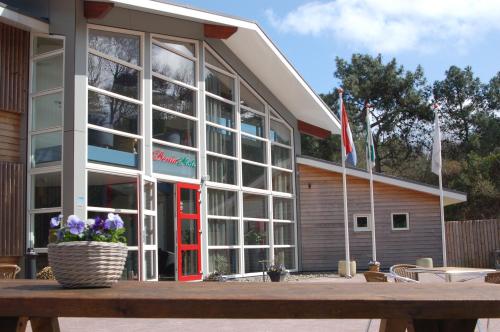 a building with a red door and some flags at Hotel DoniaState in Oost-Vlieland