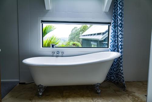 a white bath tub in a bathroom with a window at Matakana Retreat - Luxury Off Grid Lodge in Nature in Matakana