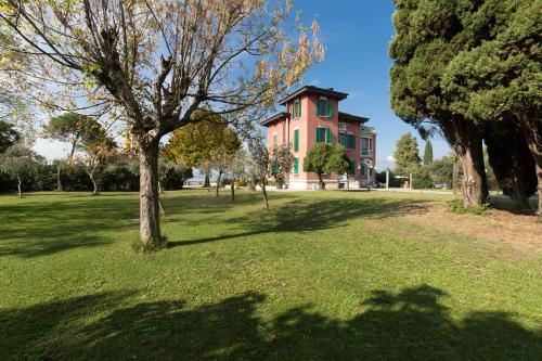 a large pink house with a tree in a field at Villa Pioppi Hotel in Sirmione