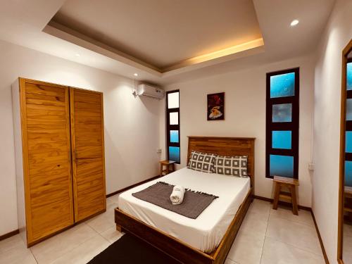 a bedroom with a bed and a cabinet and windows at Lotus D`Or Villa in Trou aux Biches