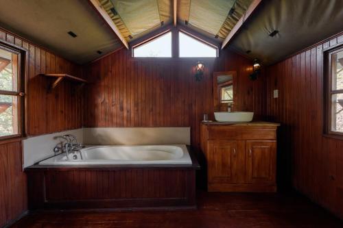 a large bath tub in a wooden bathroom with a window at Kelora Bush Camp in Hoedspruit