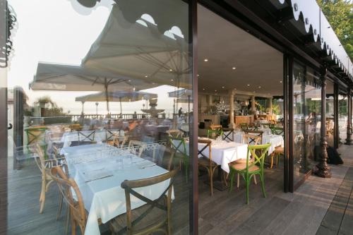 a restaurant with white tables and chairs and windows at Villa Pioppi Hotel in Sirmione