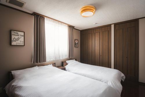 a bedroom with two white beds and a window at Villa Mimosa Myoko in Myoko