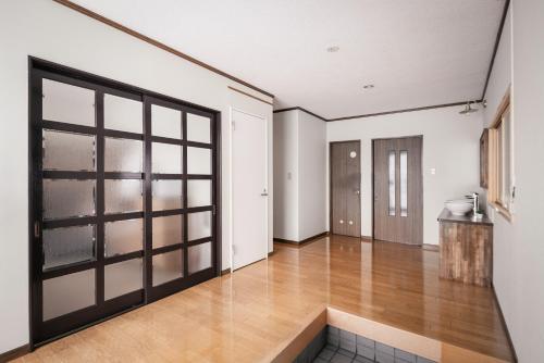 an empty room with a door and a wooden floor at Villa Mimosa Myoko in Myoko