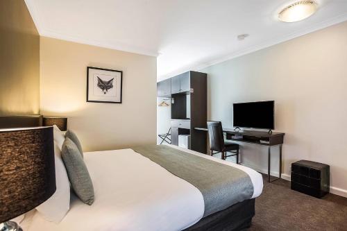 a hotel room with a bed and a desk and a television at Comfort Inn Western in Warrnambool
