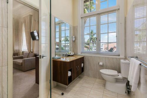 a bathroom with a toilet and a sink and a window at Quality Hotel Regent Rockhampton in Rockhampton
