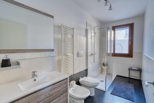 a white bathroom with a toilet and a sink at Casa Altea in Pordenone
