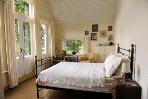1 dormitorio con 1 cama en una habitación con ventanas en Moushouk Bed and Breakfast en Oostwold